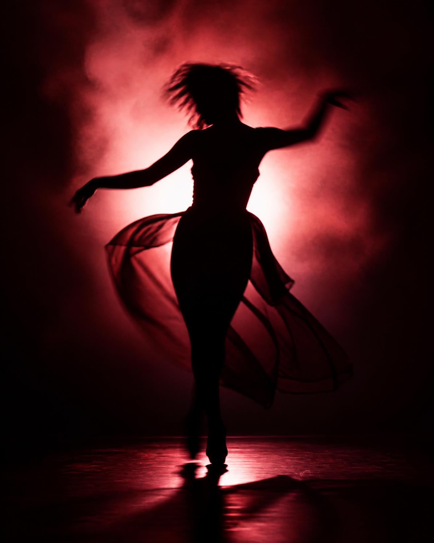 Backlit silhouette of a dancer on a smoky stage